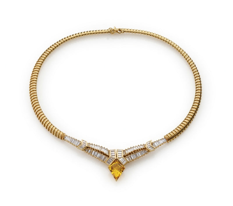 Gold necklace with baguette diamonds and a kite-shaped yellow stone at the center